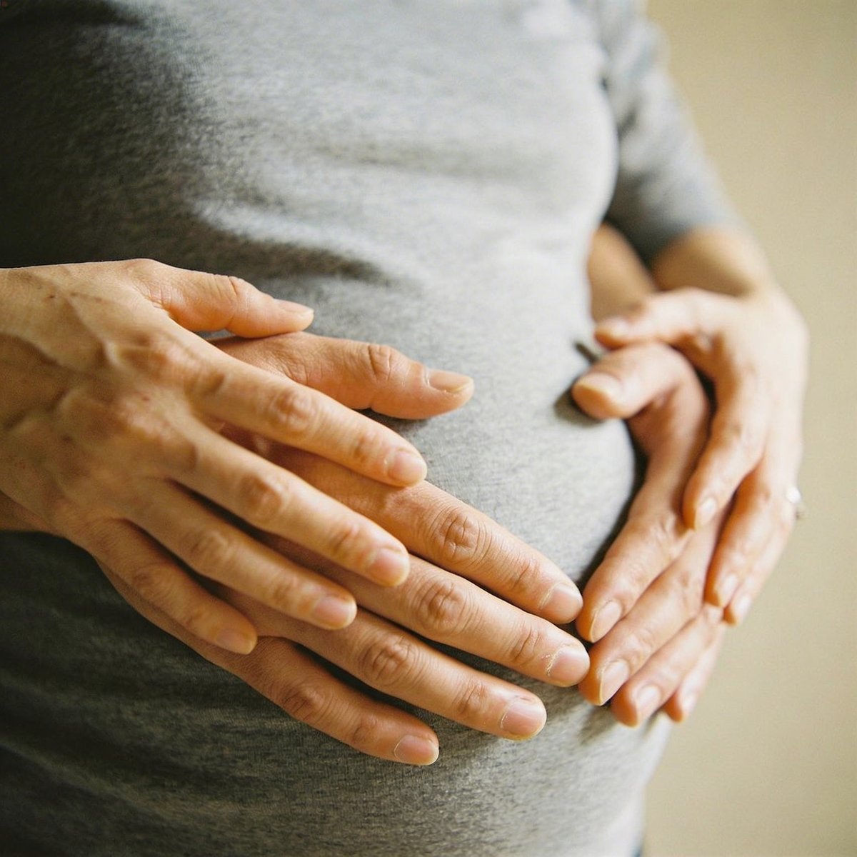 Mains en forme de cœur sur le ventre rond de la grossesse